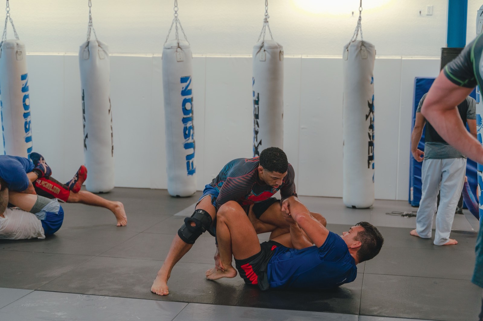 Two athletes practicing no-gi grappling on gym mats