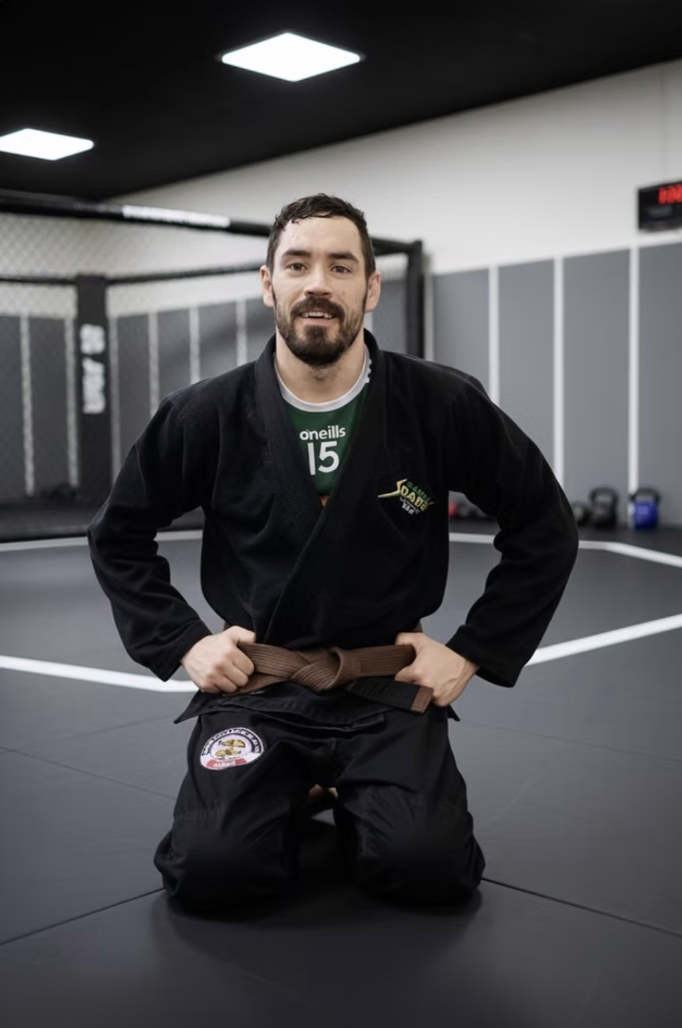 Brian O'Connor, GrapplerHQ founder, kneeling in a black gi and BJJ brown belt