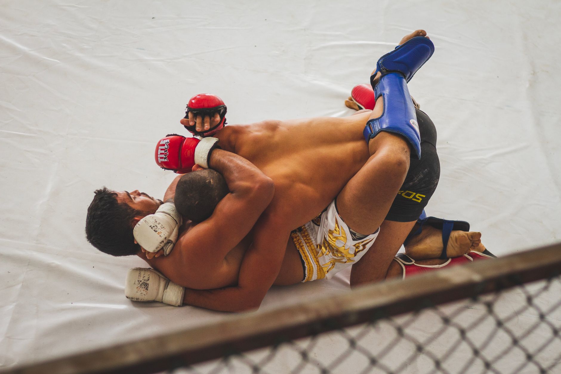 Amateur MMA fighters grappling on the ground with one controlling from top position