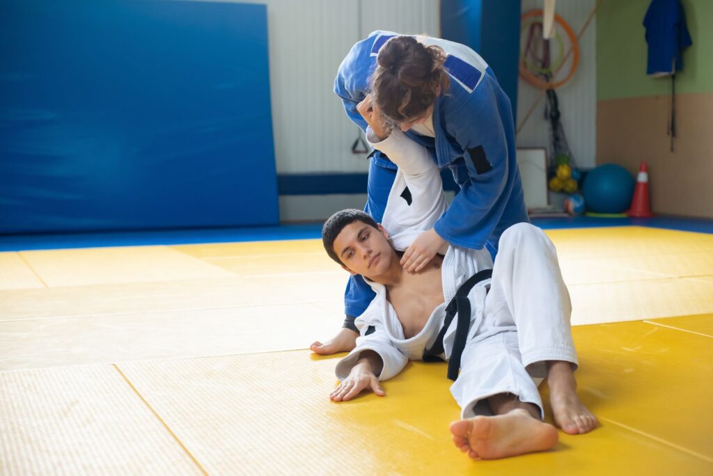 Gi grapplers training around a standing leg-control position