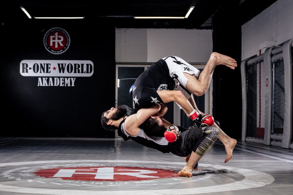 Adult martial artists drilling a dynamic takedown on padded mats