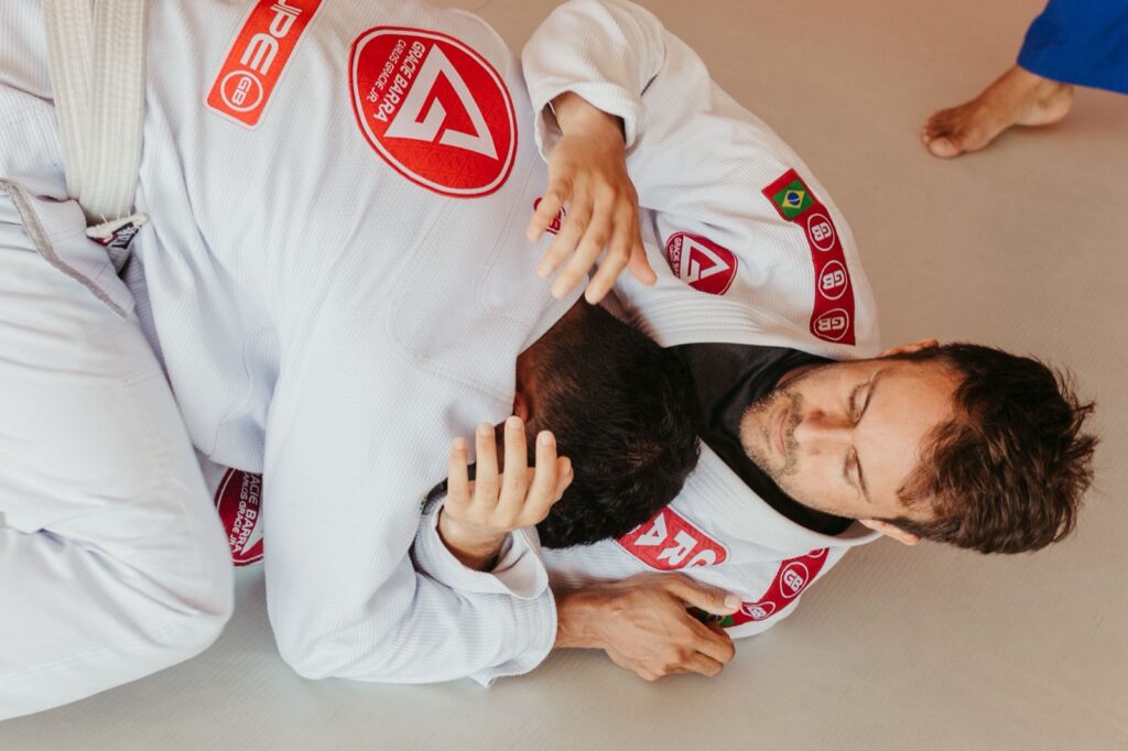 Competitors grappling in white IBJJF-legal gis with sewn academy patches