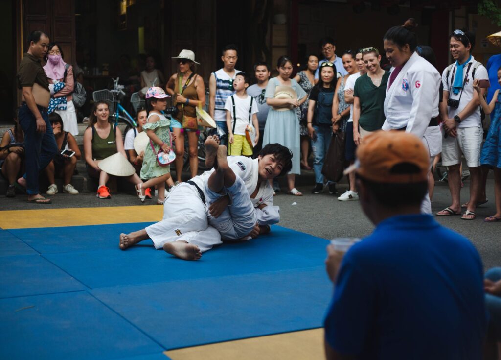 Judoka grappling on a competition mat in front of a crowd during a judo match