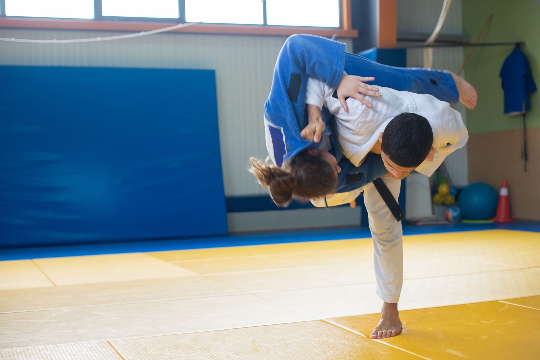 Two judoka in gis executing a throw on a tatami mat during judo practice
