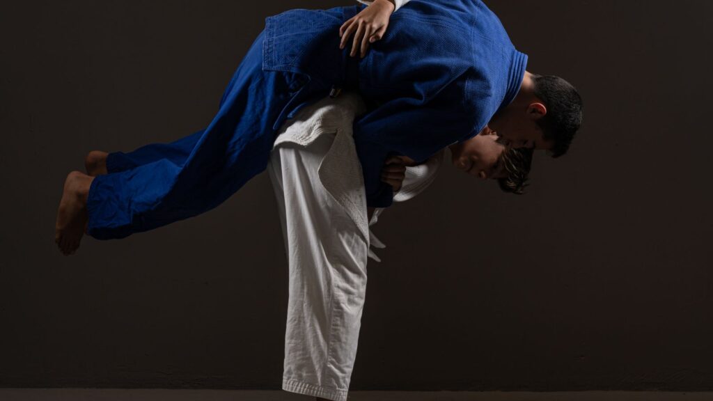 Judoka executing a hip throw on a training partner against a dark background