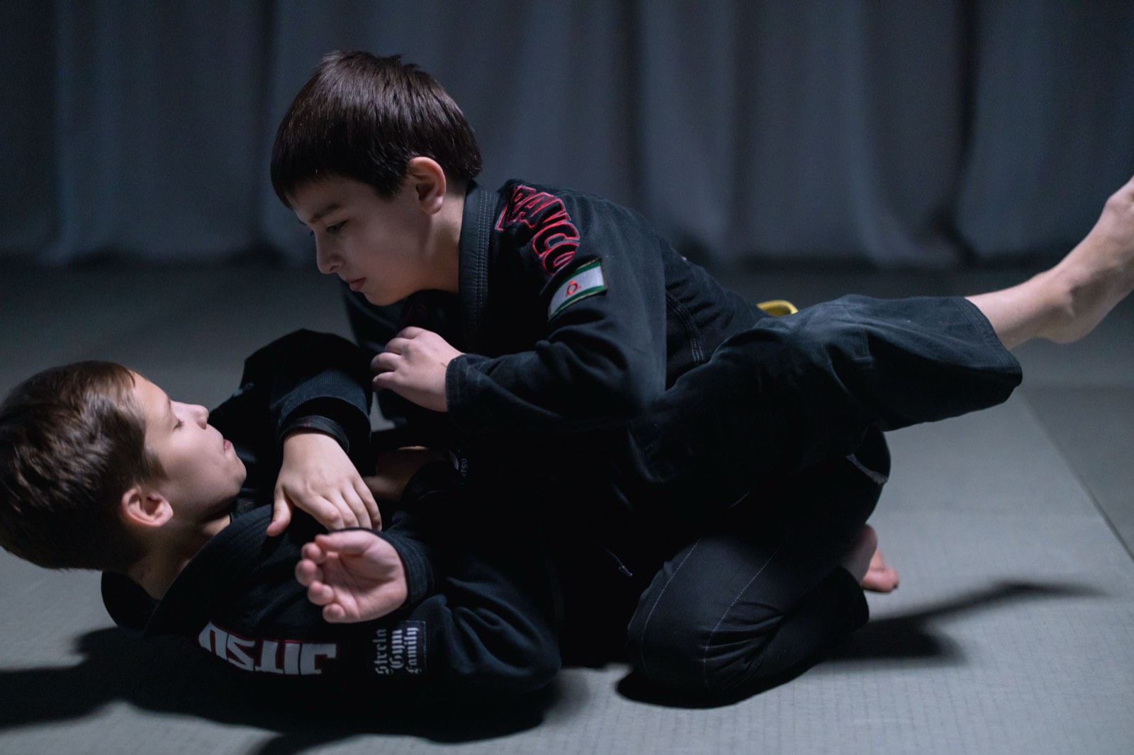 Two young jiu-jitsu students working guard passing in black gis