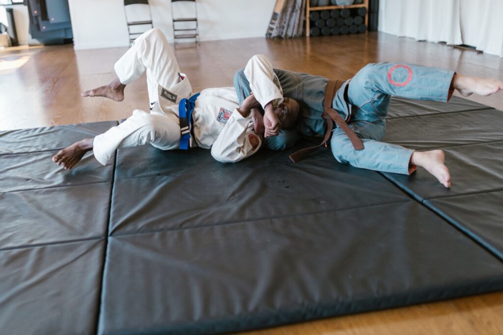 Two BJJ athletes sparring in different colored gis on academy mats