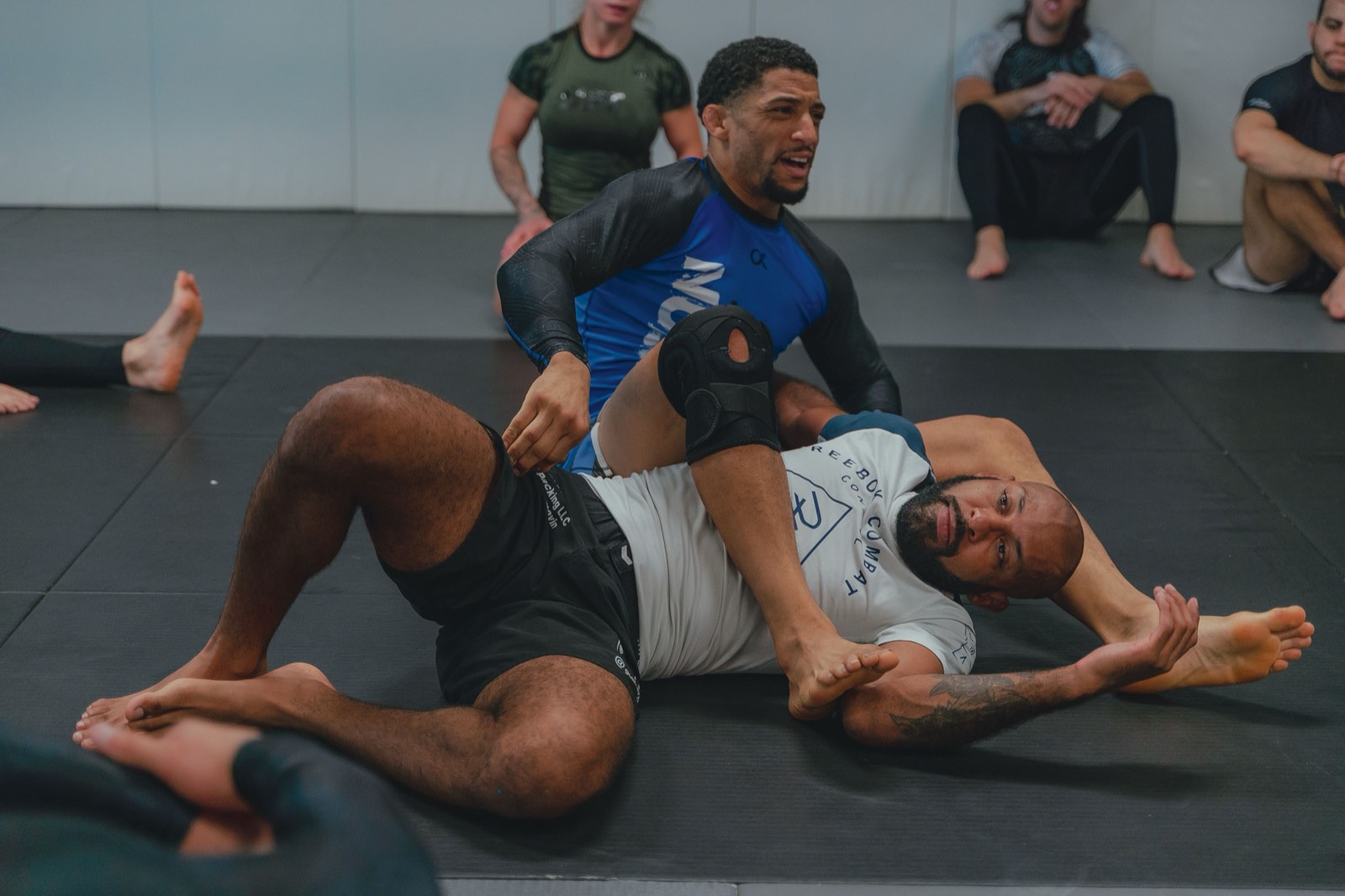 Two no-gi grapplers in rashguards training on the mats at a grappling gym