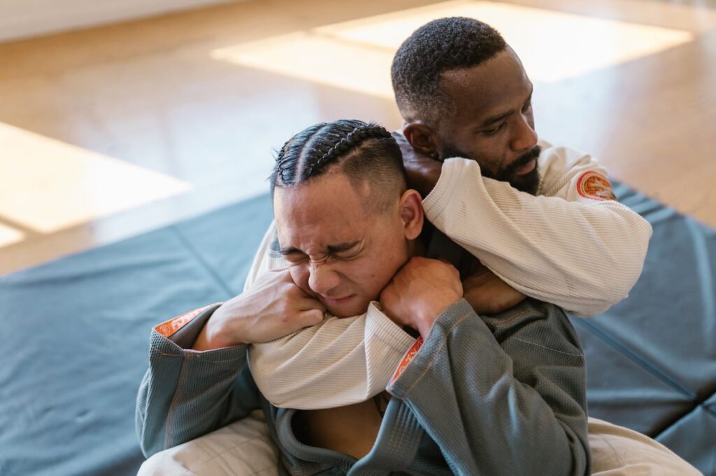 A grappler applying a rear naked choke from back control, with the choking arm under the chin and the second hand behind the head