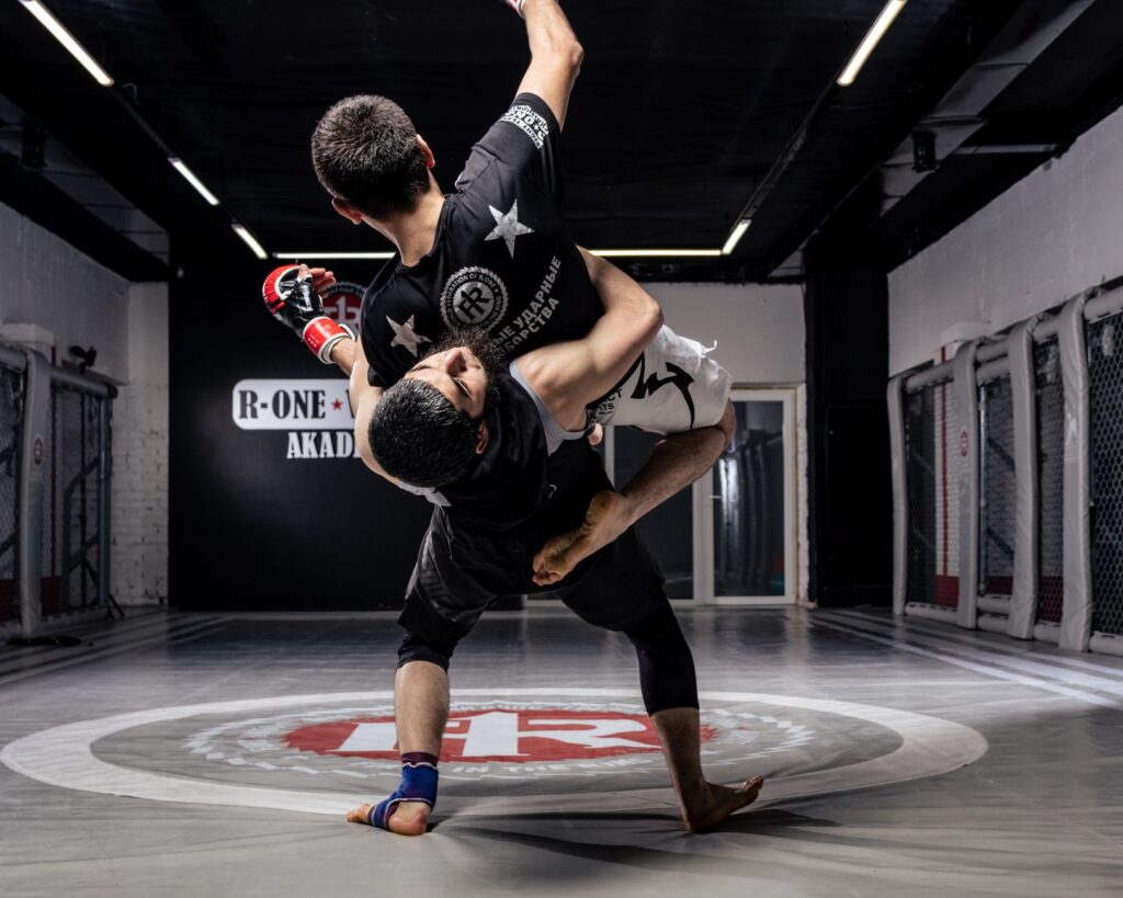 Adult martial artists practicing a controlled standing takedown