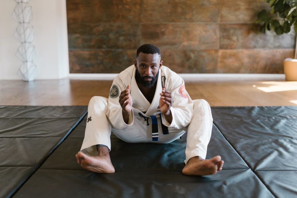 A practitioner in a white gi seated on a training mat